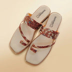A pair of women's slide sandals with square toes, featuring a white footbed and straps decorated with a red, brown, and gold floral pattern, set against a solid beige background.