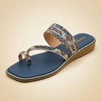 A single women's thong sandal with a blue footbed and a multi-colored geometric patterned strap, shown on a solid beige background.